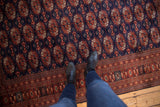 Dense wool pile and repeating gul pattern on a vintage navy blue Bokhara-style carpet.