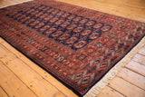 Angled perspective on a vintage Pakistani Bokhara rug with a lustrous navy and rust pile.