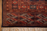 Close-up of the navy blue selvage, geometric end border, and ivory fringe on a vintage Bokhara carpet.