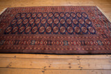 Dynamic angled view of a vintage Bokhara design carpet with a plush and lustrous wool pile.