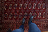 Overhead view of the repeating gul medallions on a maroon red Pakistani Bokhara carpet.