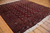 An angled view showcasing the fine wool pile and geometric gul pattern of a vintage Bokhara carpet.