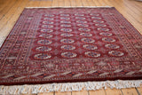 Lustrous wool pile of a vintage Pakistani Bokhara rug with geometric gul medallions in maroon wine red.