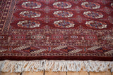 Angled view highlighting the full, plush pile and neat ivory fringe of a maroon Bokhara rug.