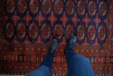 A view from above showing the plush pile and repeating red gul medallions on a dark blue Bokhara rug.
