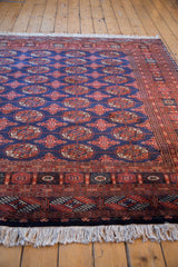 Perspective view of a vintage Bokhara rug with repeating gul medallions on a lustrous blue field.