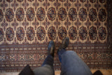 Plush wool Bokhara design carpet border with repeating gul medallions in camel, copper, navy.