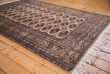 Corner of a vintage Pakistani Bokhara rug with geometric gul medallions, detailed borders and fringe.