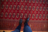 Overhead view of a vintage Pakistani Bokhara rug's plush red pile and detailed gul medallions.