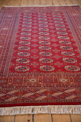 The lustrous, plush cherry red pile of a Bokhara carpet stretches away from the ivory fringe.