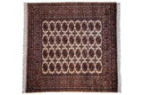 Fine vintage Pakistani Bokhara square carpet with rust and navy gul medallions on a beige field.