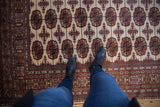 A person's view of the repeating gul medallions on a plush vintage Bokhara rug.