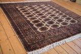Angled view of a vintage Pakistani Bokhara rug showing its repeating gul medallions and lustrous wool pile.