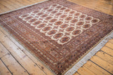 Angled view of a vintage Bokhara rug's plush pile and geometric gul pattern in rust and navy.