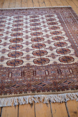 Intricate geometric border, ivory fringe, and plush wool pile on a vintage Bokhara carpet corner.