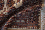 Soft, high-sheen wool pile and detailed geometric borders of a folded Pakistani Bokhara rug.