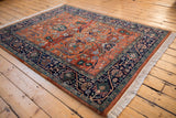 Corner of a Bijar rug with navy blue meandering vine border and rust gul ferang field.