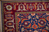 Finely detailed samovar turtle border in wine red against the dense indigo blue Herati field of a vintage rug.