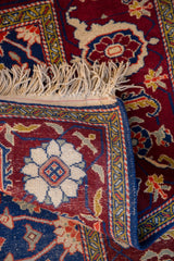 A folded corner reveals the tight hand-knotted weave and blue selvage of a vintage Russian rug.