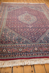 Close-up of vintage Indian rug border with intricate terracotta, navy patterns and ivory fringe.