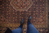 Hexagonal center medallion and intricate Herati motif in navy, apricot, and ivory on vintage Ardebil rug.