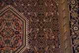 Vintage Persian Ardebil rug with navy Herati field, apricot hexagonal medallion edge, vine border.