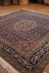 Vintage Ardebil rug corner: navy border with floral vines, apricot field, and ivory fringe.