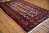 Cherry red geometric border, navy accents, and ivory field with Bokhara gul medallions.