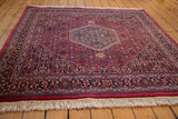 Vintage Indian carpet with thick raspberry red pile, intricate navy border, and natural beige fringe.