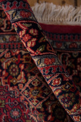 Thick pile and raspberry red, navy blue Herati motif on the rolled vintage Bijar rug.