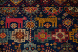 Detail of geometric red and gold animals and floral motifs on a plush cobalt blue pile.
