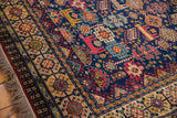 Angled close-up of the geometric border and colorful animal motifs on a vintage Indian Shiraz carpet.