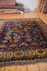 Angled view of a vintage Indian Shiraz carpet with colorful tribal motifs on a plush cobalt blue field.