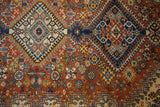 Hand knotted Indian Shiraz rug detail: chestnut field, navy blossoms, geometric border.