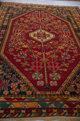 Hand-knotted cherry red field with vinery, gold blossoms, and navy blue Shiraz border.