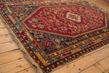 Shiraz rug corner: cherry red field with vinery, navy border, original selvage, fringe.