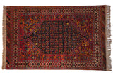 Vintage Indian Afshar design carpet with a navy floral medallion on a geometric cherry red field.