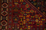 Close-up of a vintage Afshar carpet's geometric animal motifs in gold and blue on a cherry red field.