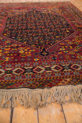 A low perspective of the vintage rug's hand-knotted fringe and detailed border pattern.