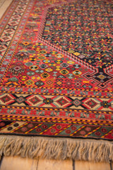 Angled view of a vintage Afshar design carpet showing its detailed geometric borders and fringe.