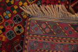 Secured corner of a vintage Afshar design carpet showing the full pile, geometric border, and fringe.