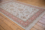 Ivory field with oversized floral palmettes, pale terracotta curvilinear border of an Indian Mahal carpet.
