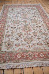 Terracotta border with floral motifs in slate blue, sea foam, and beige, and ivory fringe.