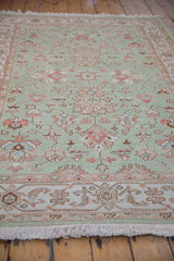 Detail of seafoam Indian Mahal rug with floral palmettes, ivory border, and fringe.