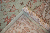 Indian Mahal carpet corner with seafoam, terracotta floral palmettes, ivory border, and fringe.