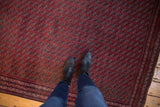 Vintage Beljic rug's repeating floral gul pattern in pomegranate red, viewed from above for scale.