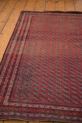 Angled detail of the meandering vine border and repeating floral gul motifs on a fine Beljic rug.