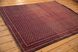 Angled view of a vintage Beljic rug showing its dense pile and repeating red gul motif.