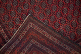 Fine hand-knotted back and red gul motif pile shown on a vintage Beljic rug's folded corner.