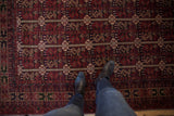 Detailed cherry red and charcoal navy Belouch rug with intricate vinery and boteh patterns.